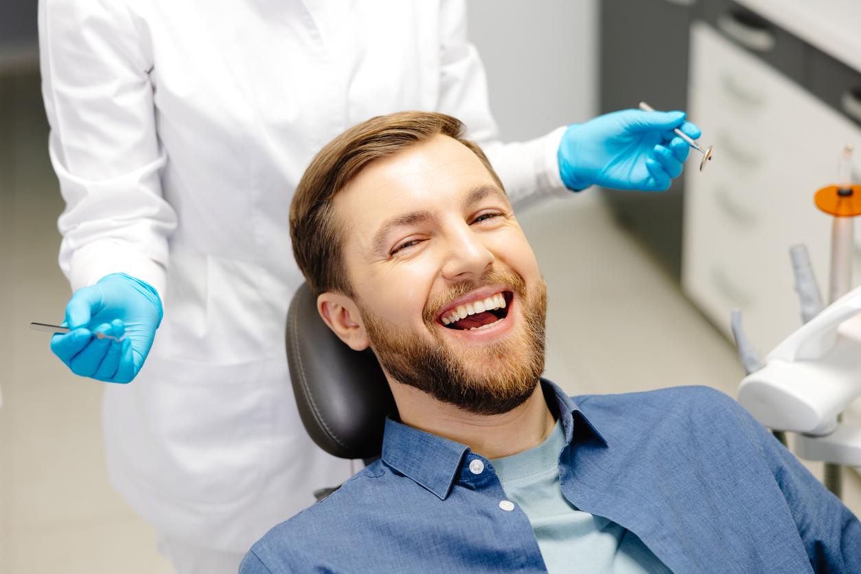 A man who is about to get a dental cleaning smiling in a dental chair
